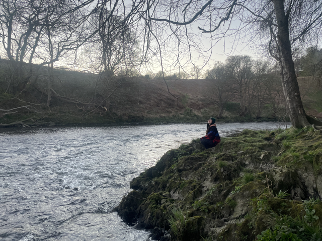 nera crouched on the bank of a river